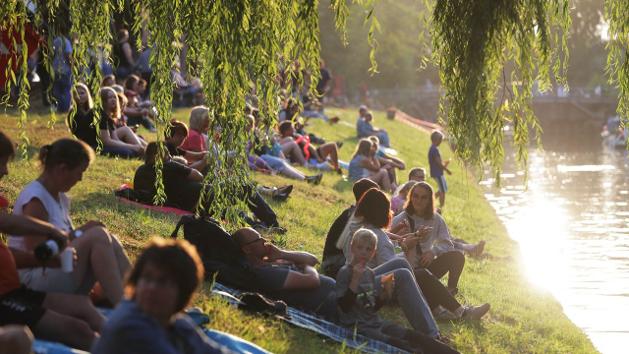 Menschen sitzen am Flussufer. (Quelle: M. Staudt/ grafikfoto.de) Menschen sitzen am Flussufer.