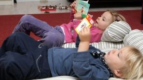 Kinder schauen sich ein Buch an (Quelle: R. Seeberg / grafikfoto.de) Kinder schauen sich ein Buch an